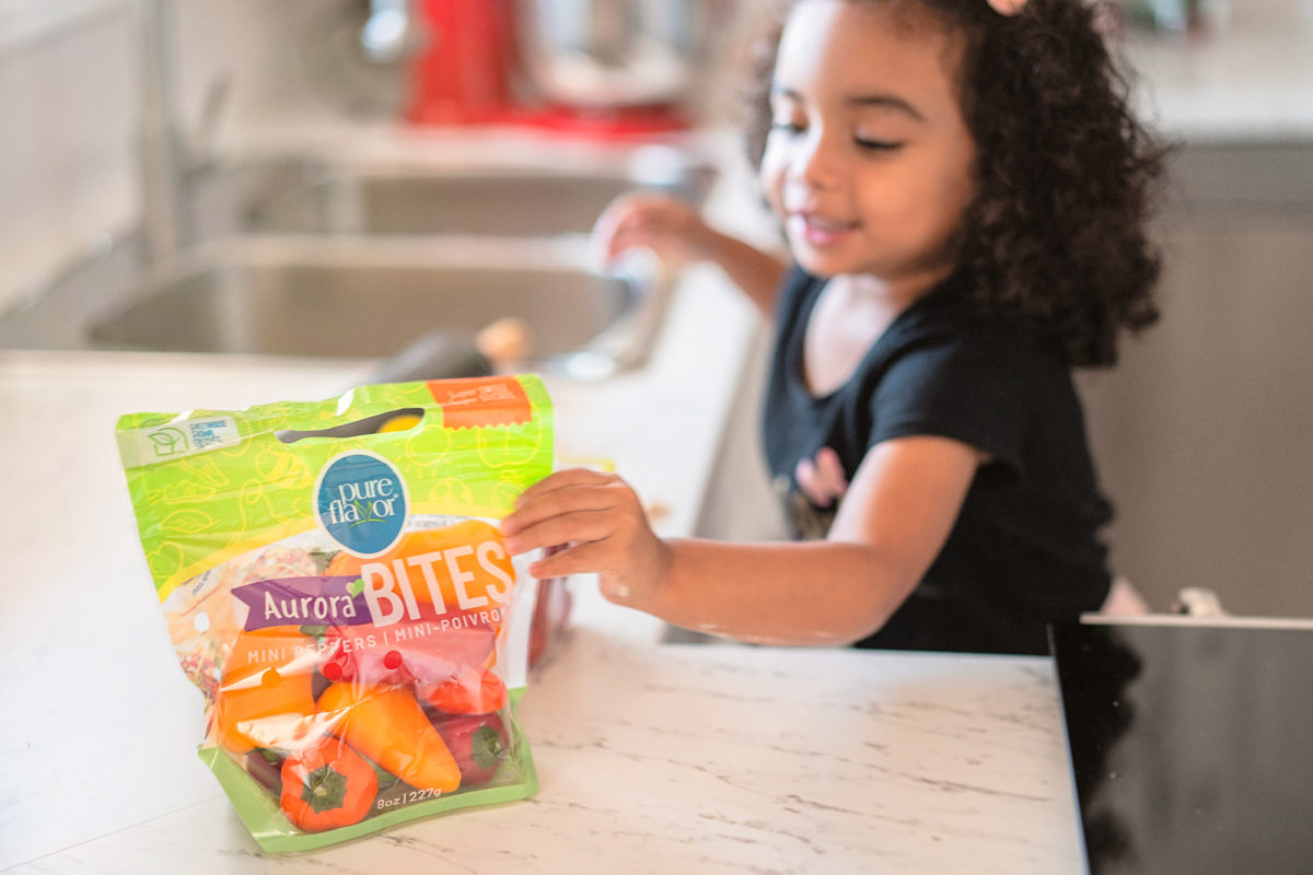 girl in kitchen eating mini peppers