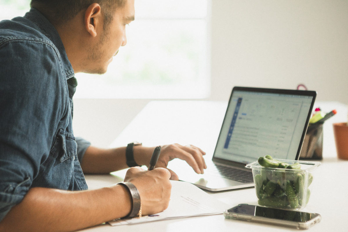 man working on laptop with pack of uno bites as a snack
