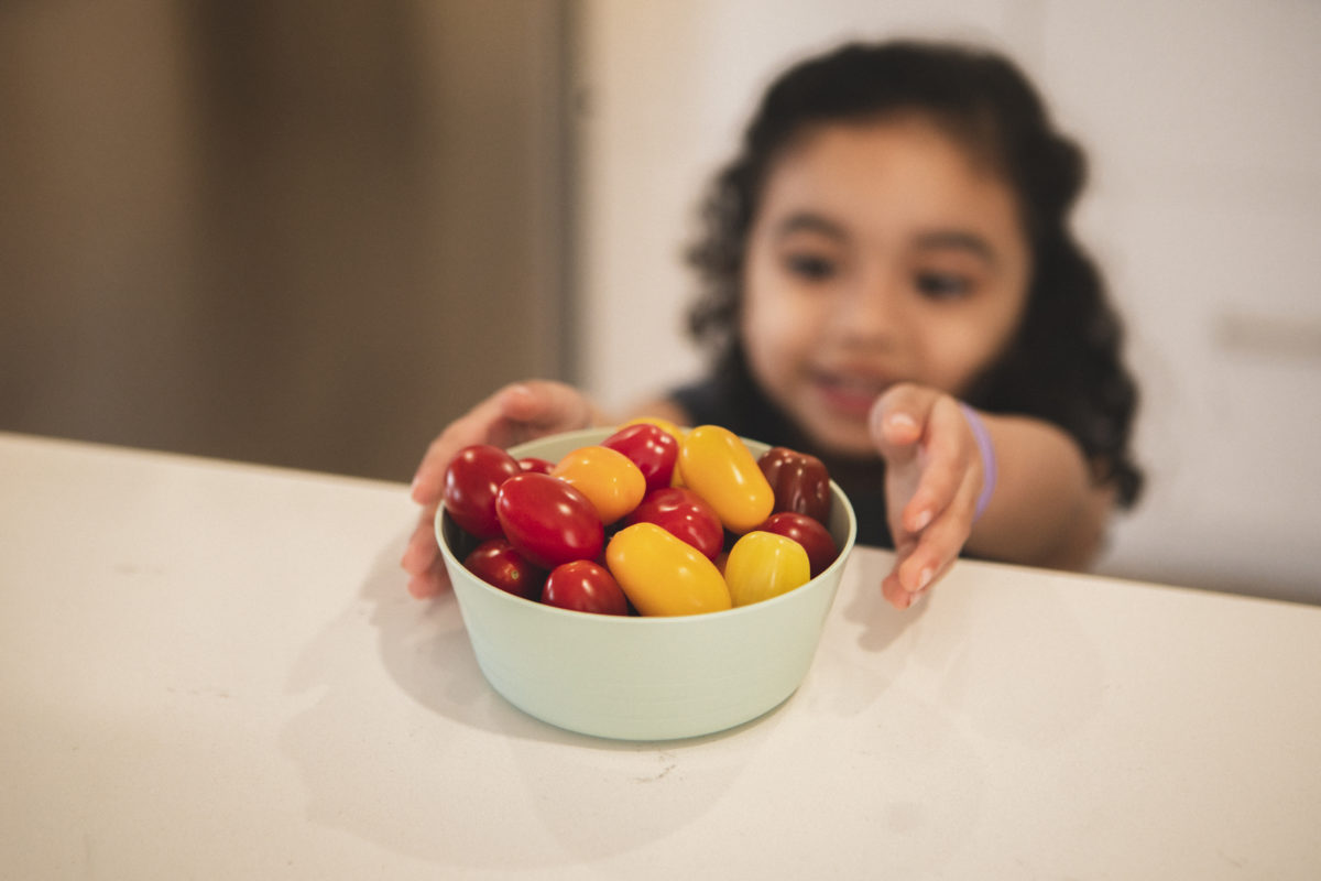 Little girl reaching sangria medley tomatoes