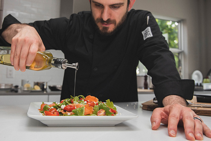 Chef dressing salad in kitchen