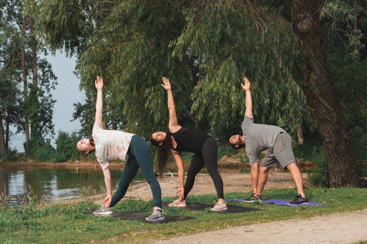 3 Friends doing triangle pose in the park