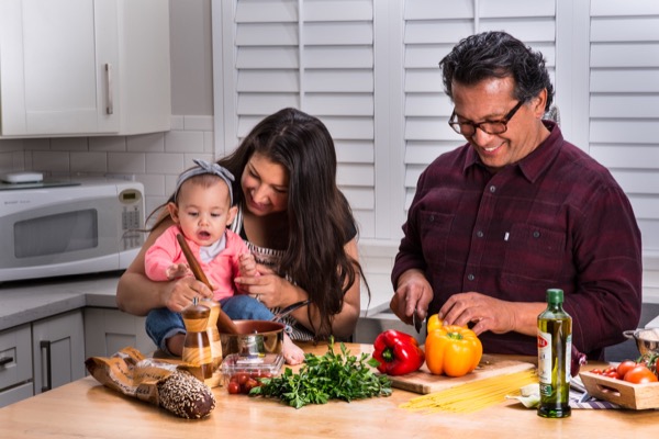 Couple with baby in kitchen cooking dinner