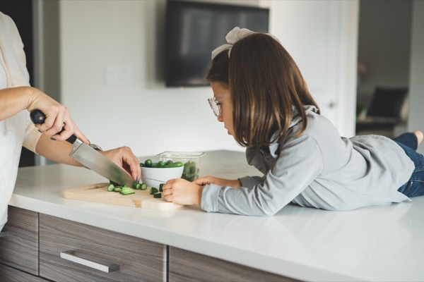 Girl chopping vegetables with her mom