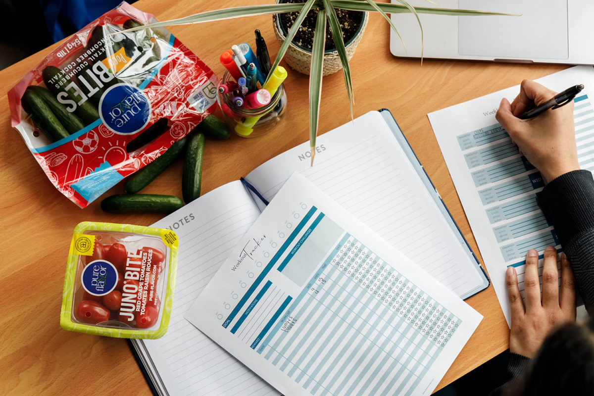 Table with fitness planner, notebook and snacks.