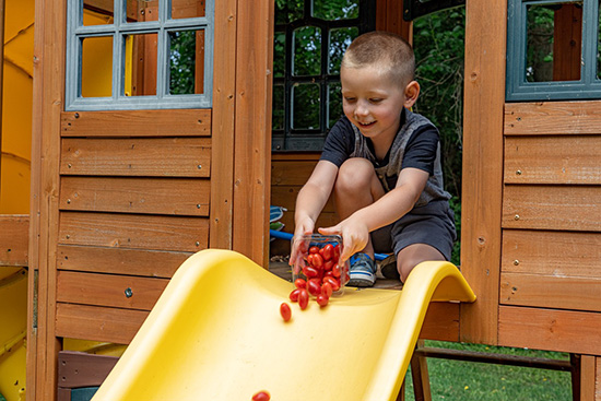 a boy playing with tomatoes on a slide