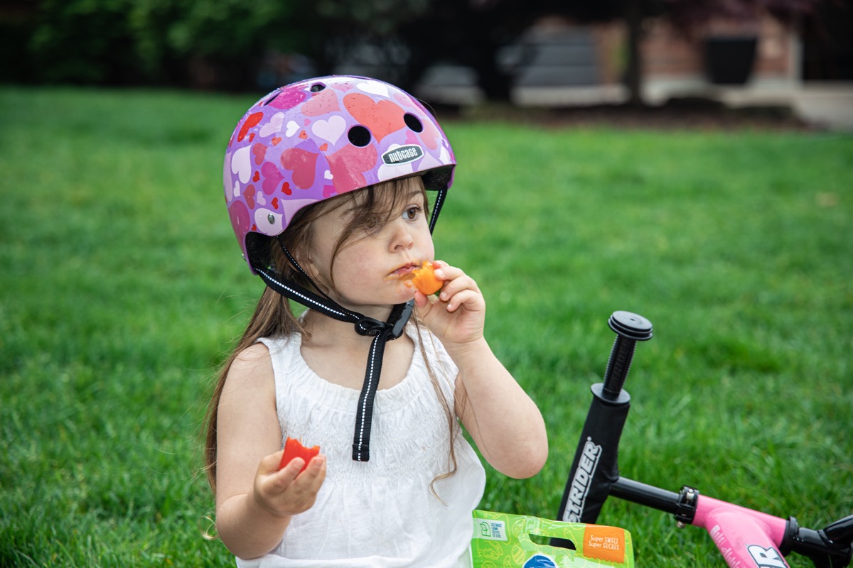 Girl riding a bike and eating mini pepper