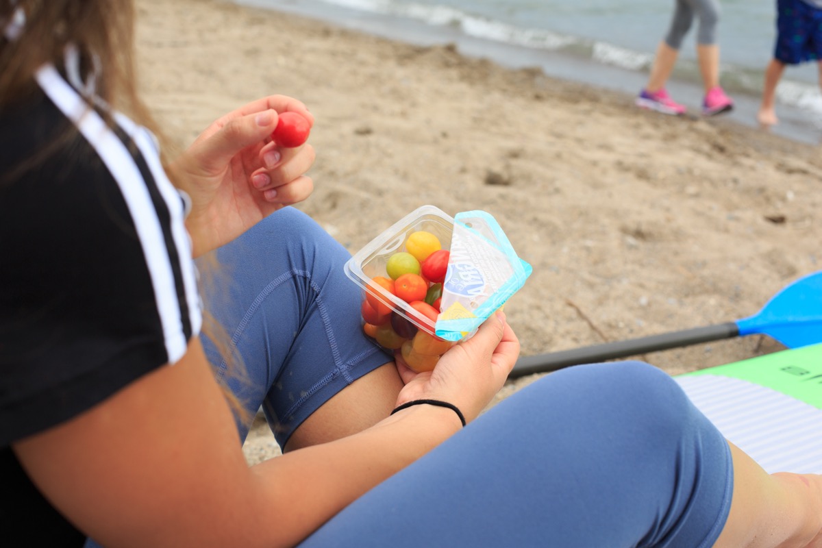 Girl grabbing snacking tomatoes at the beach