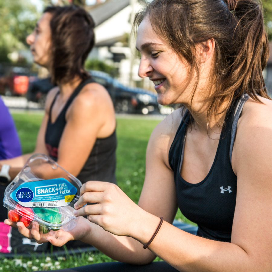 a woman eating a Pure Flavor snack at the park