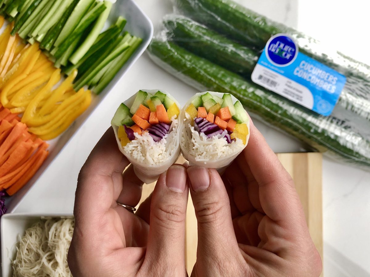Hands holding 2 vegetarian rice wraps,. Pure flavour cucumbers pack on a side.